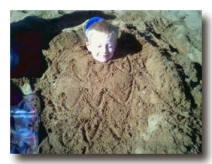 The lad buried in sand.